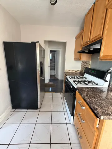 a kitchen with stainless steel appliances granite countertop a refrigerator a stove and a sink