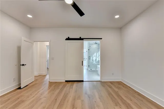 a view of an empty room with wooden floor and a ceiling fan
