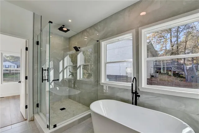 a bathroom with a granite countertop tub shower and mirror