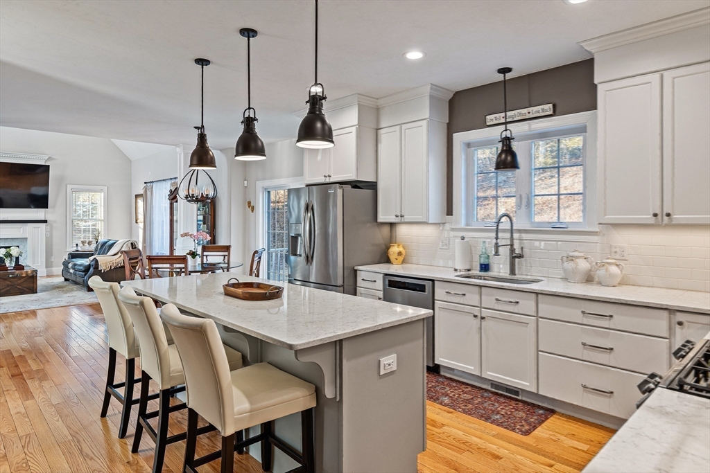7 Jewell Crossing Mendon, MA 01756 - Photo 13 of 42 a kitchen with stainless steel appliances kitchen island granite countertop a table chairs and a refrigerator