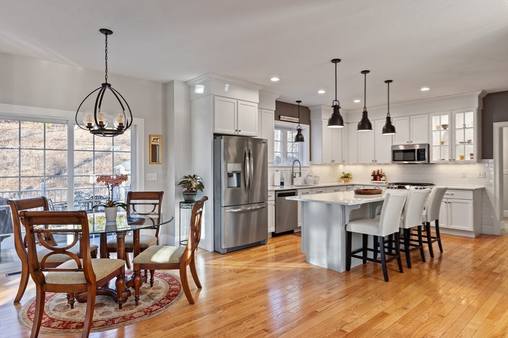 7 Jewell Crossing Mendon, MA 01756 - Photo 9 of 42 a kitchen with stainless steel appliances kitchen island granite countertop a dining table chairs and white cabinets
