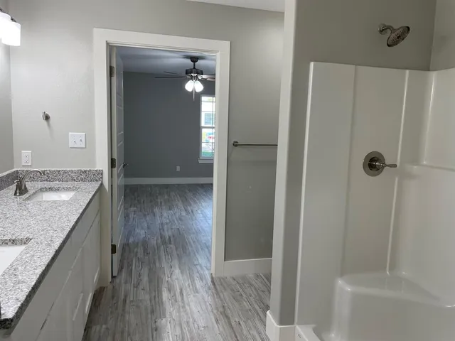 a bathroom with a granite countertop sink a mirror and shower