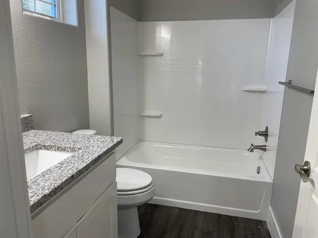 a bathroom with a granite countertop sink toilet and bathtub