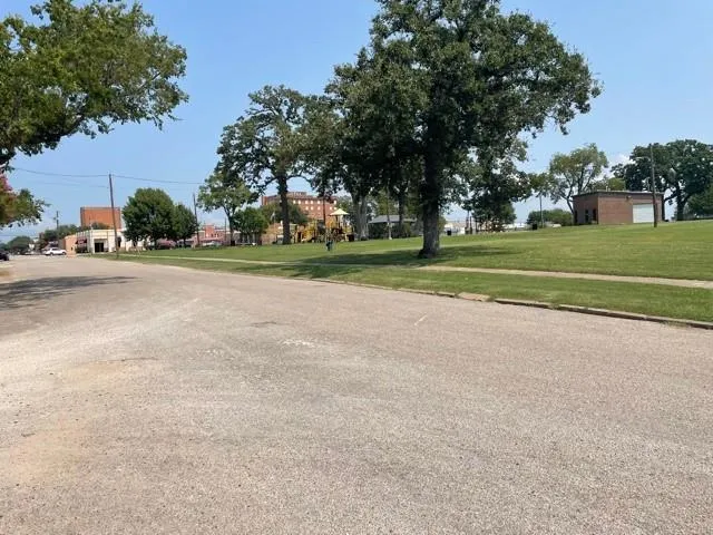 a view of a golf course with a big yard and a large trees