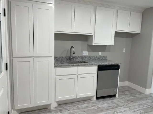 a kitchen with granite countertop white cabinets and sink