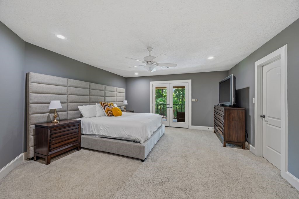 27722 Tiverton Court Spring, TX 77386 - Photo 22 of 33 A Private Escape Above It All: One upstairs bedroom enjoys the luxury of its own en-suite bathroom, spacious walk-in closet, and a private balcony overlooking the sparkling pool and surrounding greenery—a peaceful place to unwind and take in the beauty of the estate.