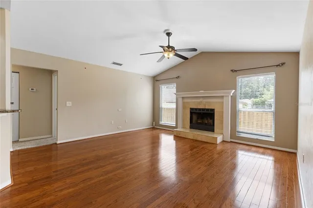 a view of an empty room with wooden floor fireplace and a window