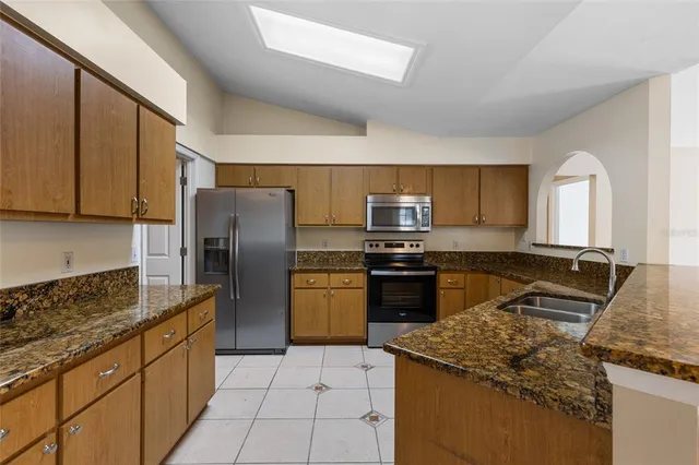 a kitchen with stainless steel appliances granite countertop a stove refrigerator and sink