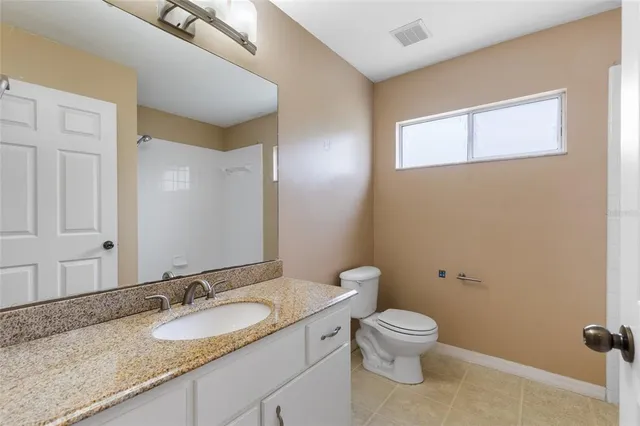 a bathroom with a granite countertop toilet a sink and a mirror