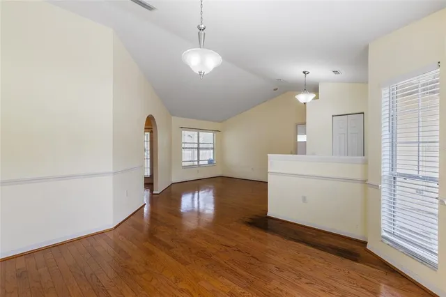 a view of a kitchen and an empty room with wooden floor