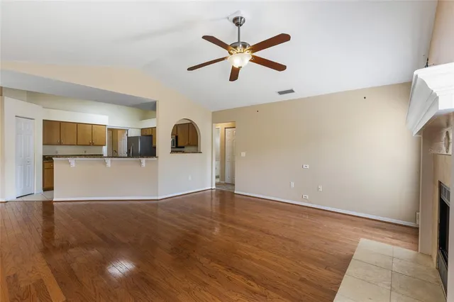 a view of a livingroom with a ceiling fan a kitchen space with wooden floor and a ceiling fan
