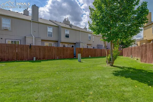 a view of a backyard with large trees and wooden fence