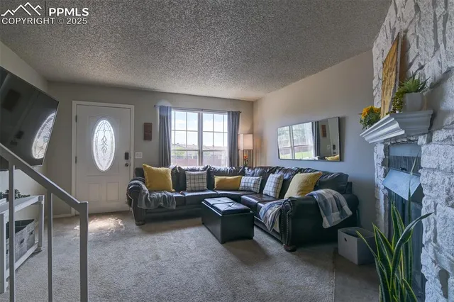 a living room with furniture a fireplace a potted plant and a window