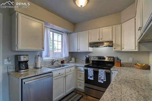 a kitchen with granite countertop a sink a stove and cabinets