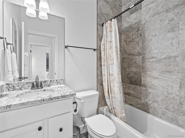 a bathroom with a granite countertop sink a toilet and shower