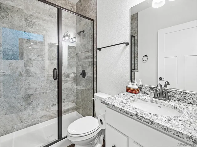 a bathroom with a granite countertop sink a toilet and shower