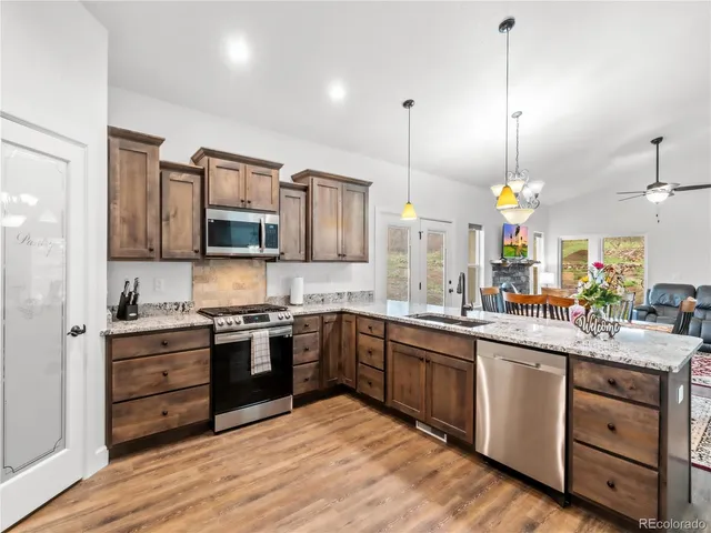a kitchen with stainless steel appliances granite countertop a sink a stove and a wooden floors