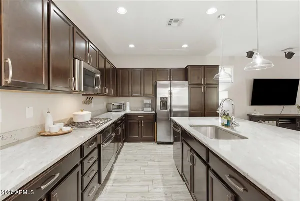a kitchen with stainless steel appliances granite countertop a stove a sink a microwave a refrigerator and cabinets