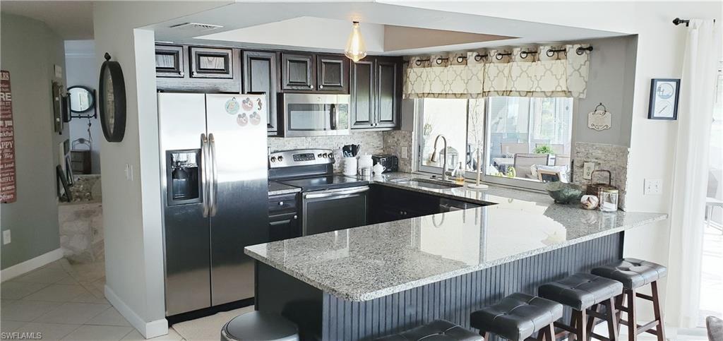 391 Torrey Pines Point Naples, FL 34113 - Photo 12 of 32 a kitchen with stainless steel appliances granite countertop a refrigerator a sink and a stove