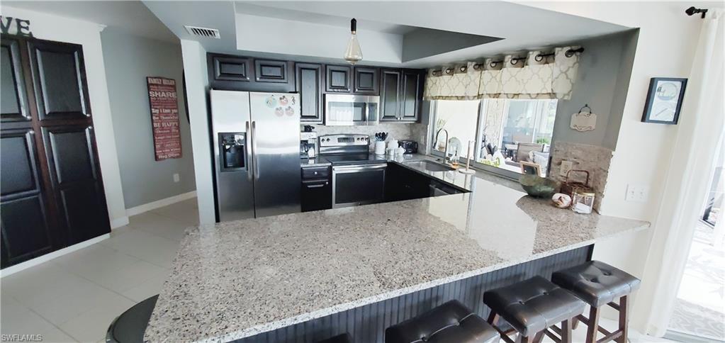 391 Torrey Pines Point Naples, FL 34113 - Photo 13 of 32 a kitchen with stainless steel appliances granite countertop a refrigerator a sink a stove and white cabinets