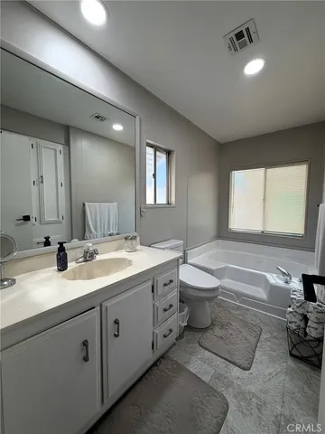 a bathroom with a granite countertop toilet a sink and mirror