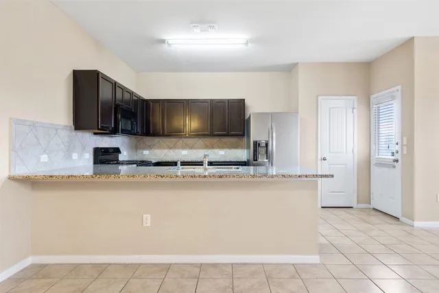 a kitchen with stainless steel appliances granite countertop a stove refrigerator and a sink