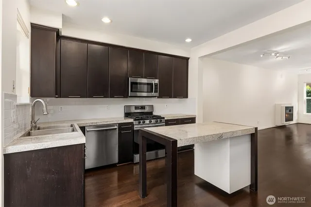 a kitchen with stainless steel appliances a stove a sink a microwave a refrigerator and cabinets