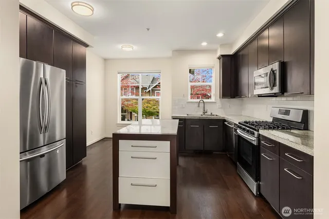 a kitchen with stainless steel appliances granite countertop a stove a sink and a refrigerator
