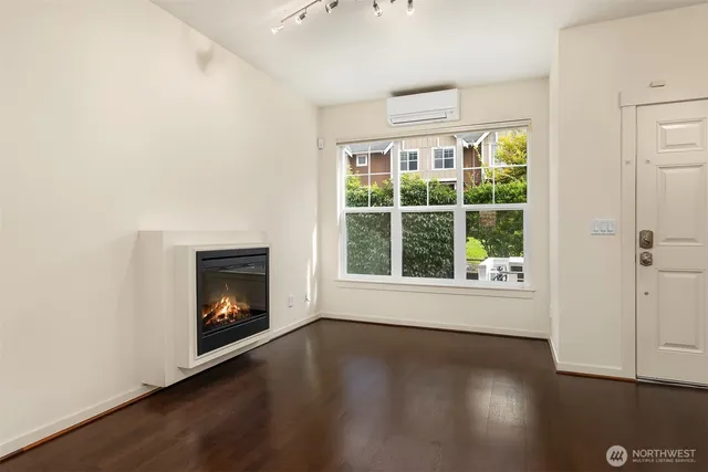 an empty room with wooden floor fire place and windows