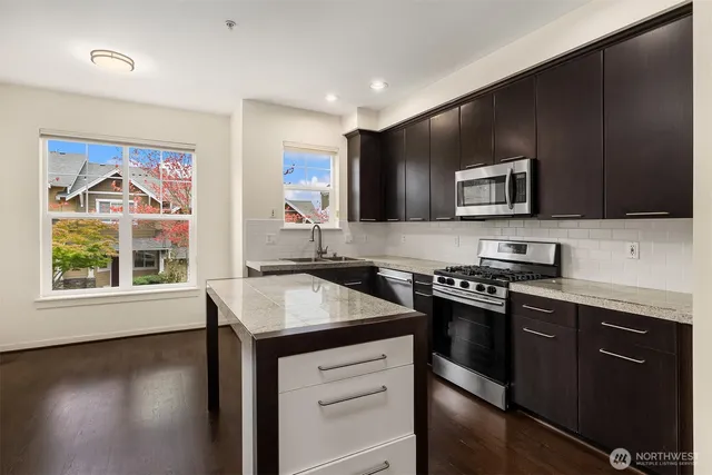 a kitchen with stainless steel appliances granite countertop a stove a sink and a microwave