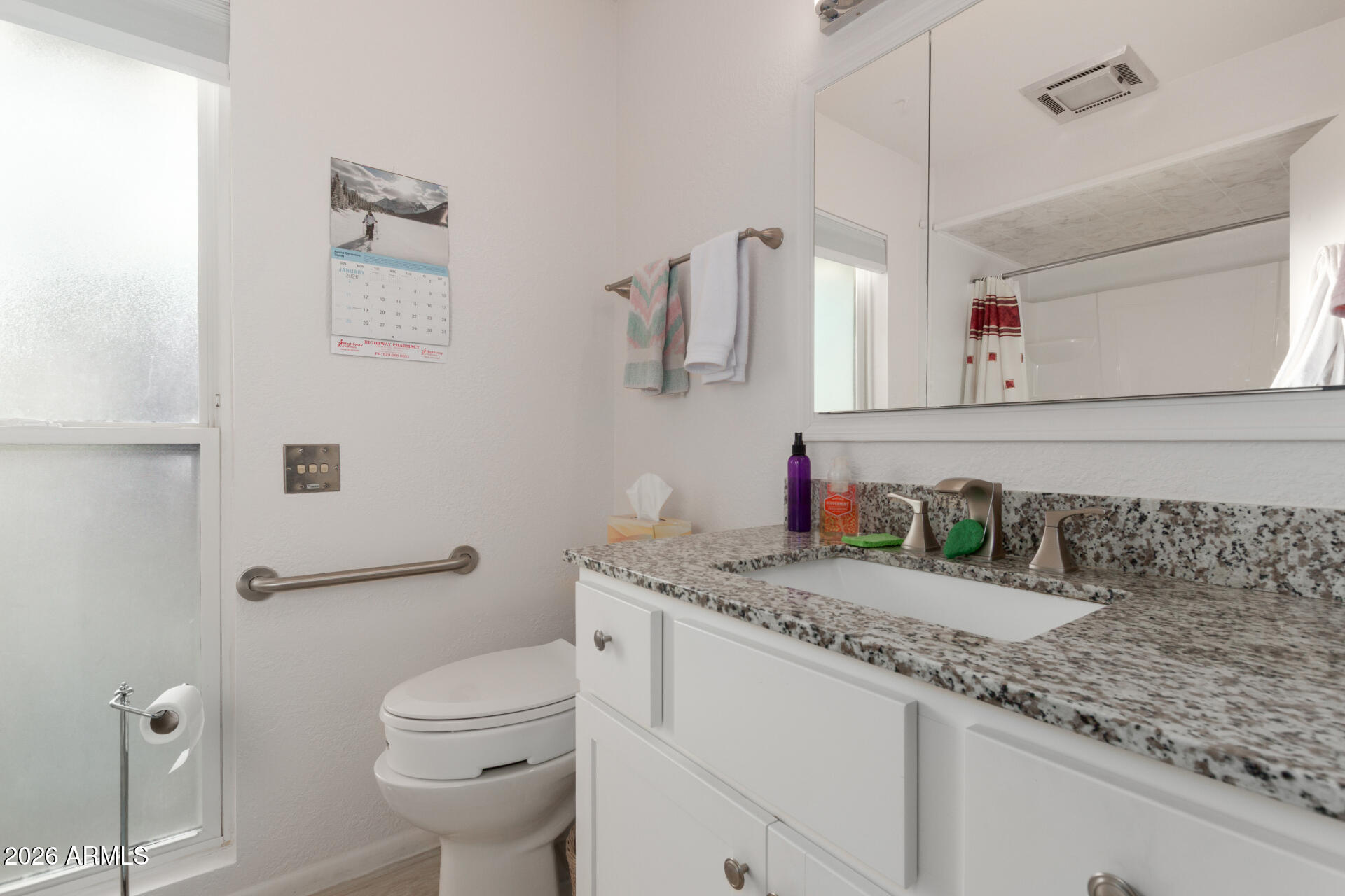 9705 West Oak Ridge Drive Sun City, AZ 85351 - Photo 13 of 23 a bathroom with a granite countertop sink a toilet and a mirror