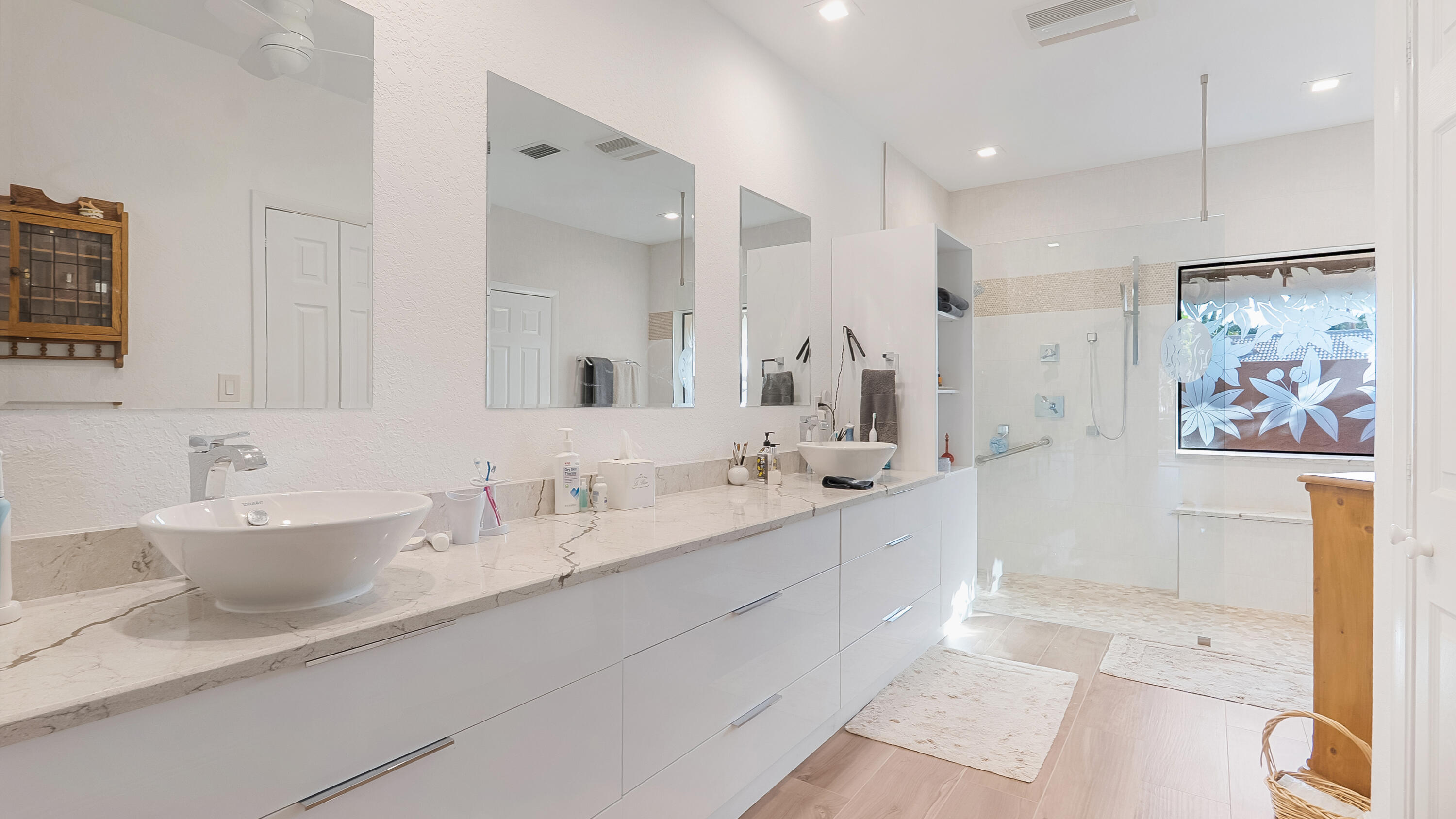 10767 Boca Woods Lane Boca Raton, FL 33428 - Photo 32 of 64 a bathroom with double vanity sinks a large mirror and a shower