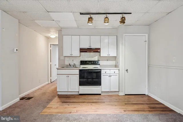 a kitchen with a refrigerator and white cabinets