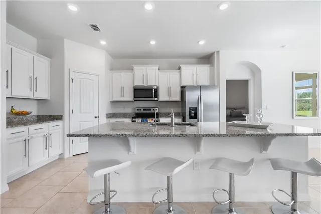 a kitchen with stainless steel appliances granite countertop a sink refrigerator and cabinets