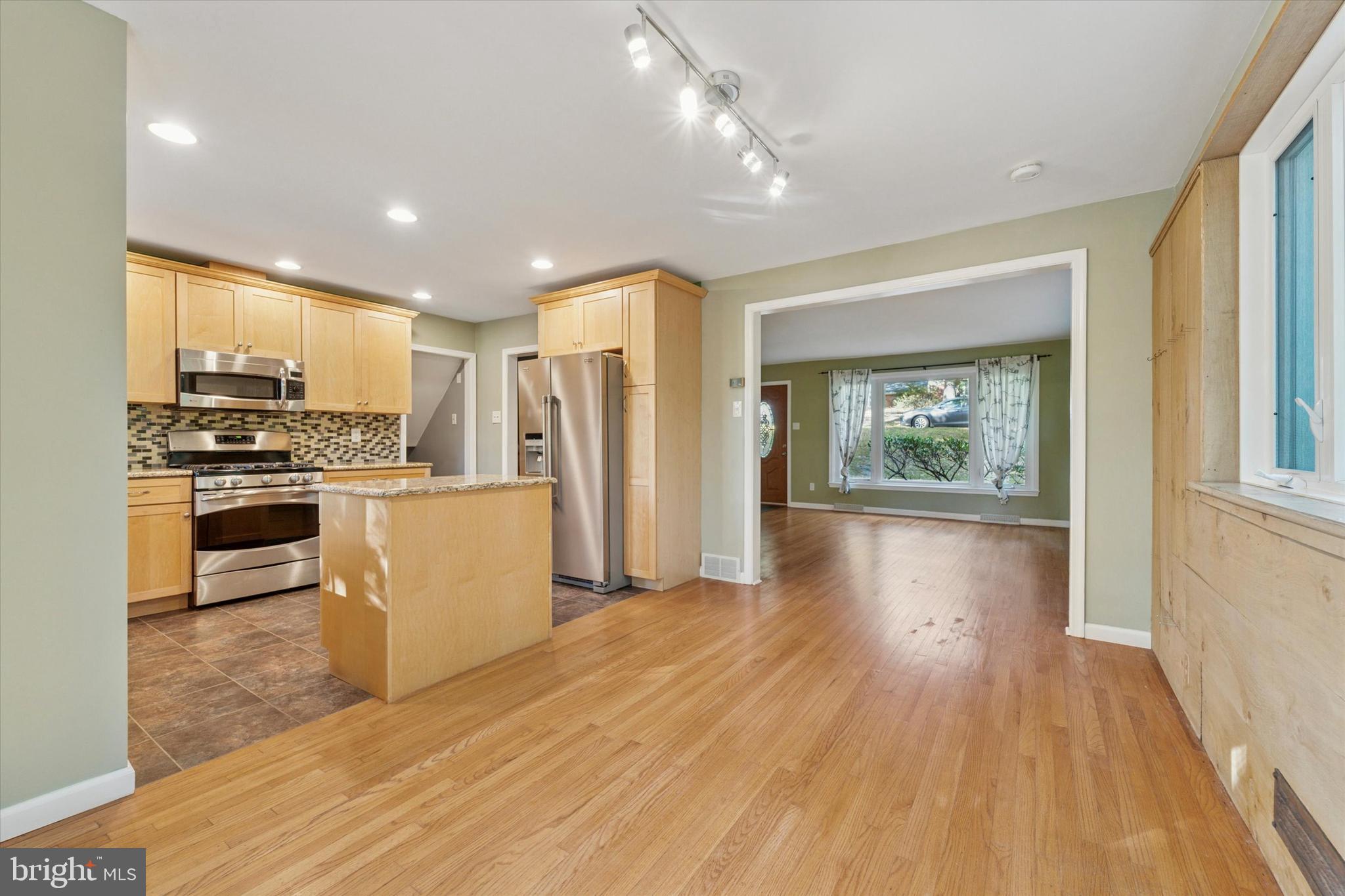 679 Crestwood Road Wayne, PA 19087 - Photo 7 of 19 a kitchen with stainless steel appliances a refrigerator a stove top oven a sink dishwasher and a dining table with wooden floor