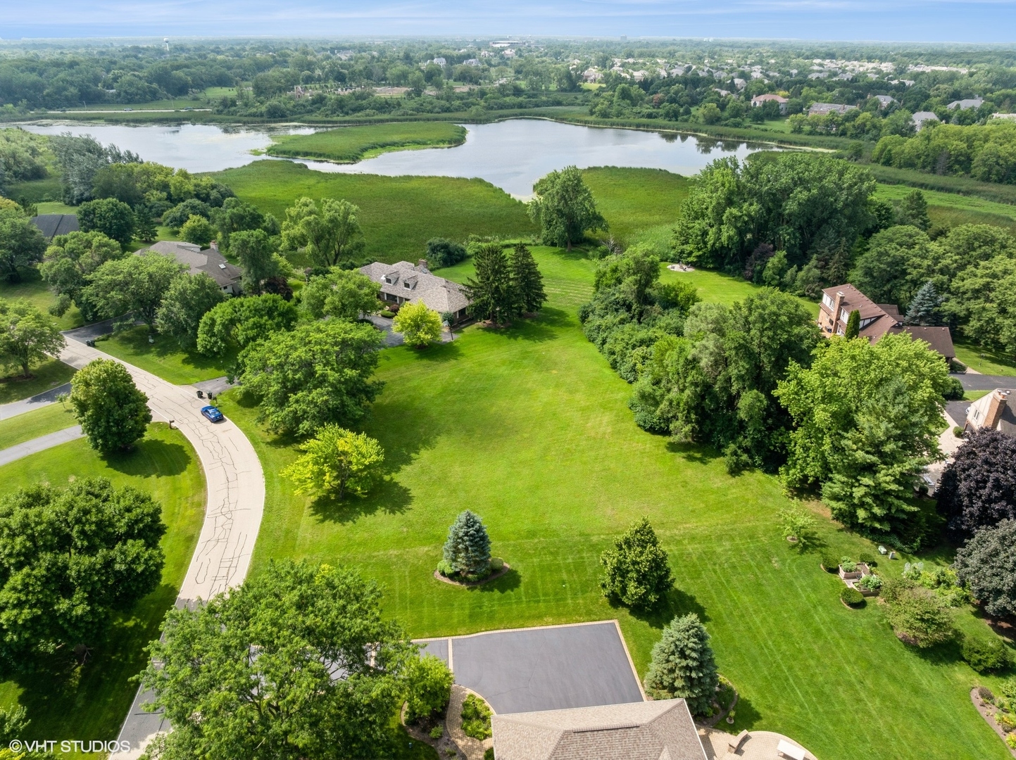 2204 Shetland Road Inverness, IL 60010 - Photo 1 of 5 an aerial view of green landscape with trees houses and lake view