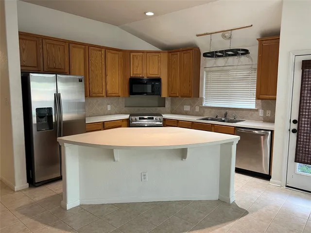 a kitchen with kitchen island a sink refrigerator and microwave