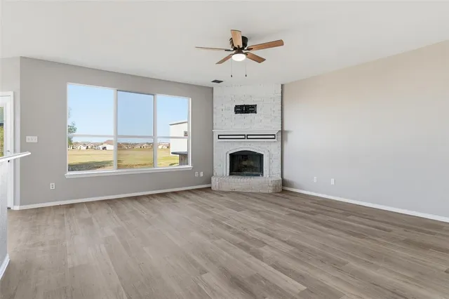 a view of a livingroom with a fireplace a ceiling fan and wooden floor