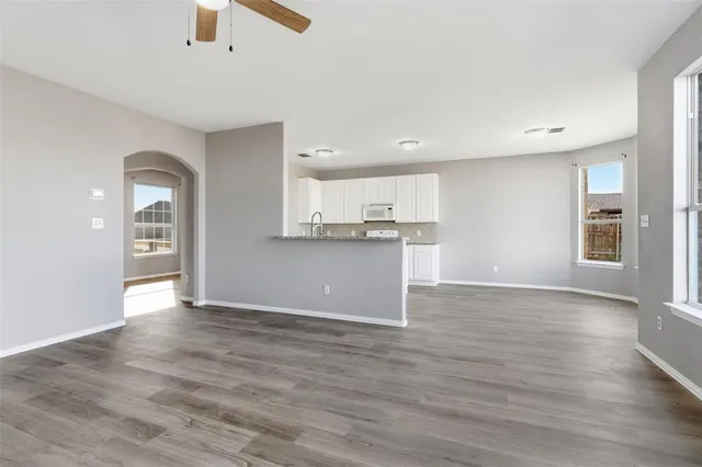 a kitchen with granite countertop white cabinets and wooden floor