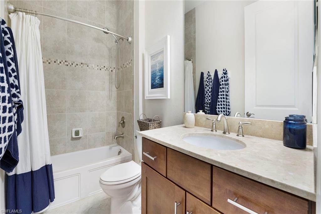 1410 Redona Way Naples, FL 34113 - Photo 25 of 50 a bathroom with a granite countertop sink a toilet a mirror a bathtub and shower