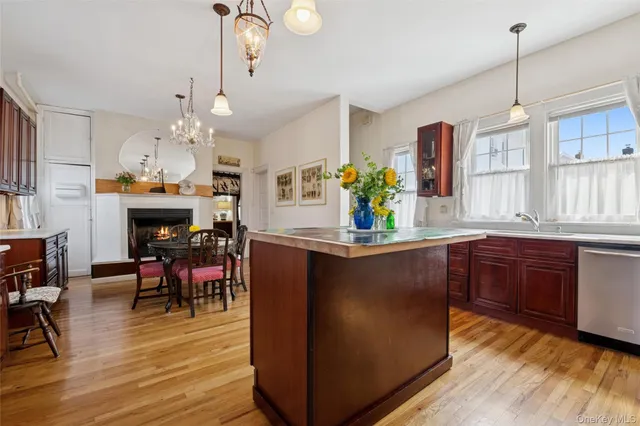 a kitchen with stainless steel appliances granite countertop a refrigerator a sink dishwasher a dining table and chairs with wooden floor