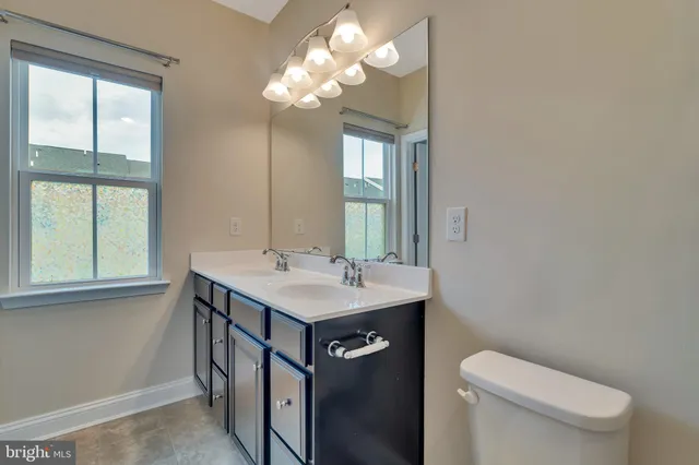 a bathroom with a sink a toilet a mirror and a window