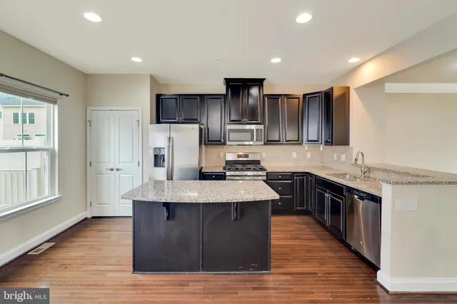a large kitchen with stainless steel appliances wooden floors and wooden cabinets