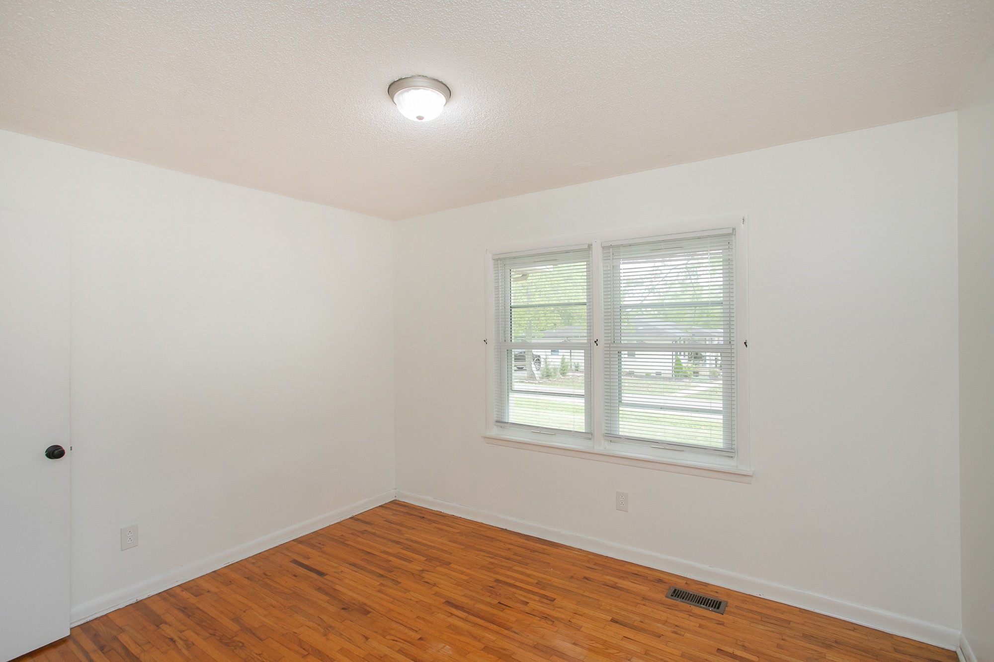 129 Poplar Street Eagleville, TN 37060 - Photo 17 of 23 an empty room with wooden floor and windows