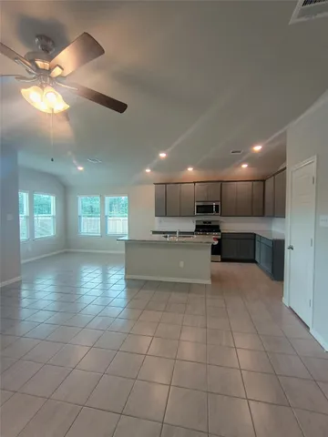 a view of an empty room and kitchen with sink windows