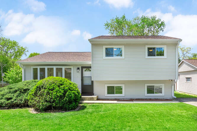 a front view of a house with a yard and green space