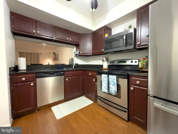a kitchen with stainless steel appliances granite countertop a refrigerator a sink dishwasher a stove top oven a refrigerator with island and chairs