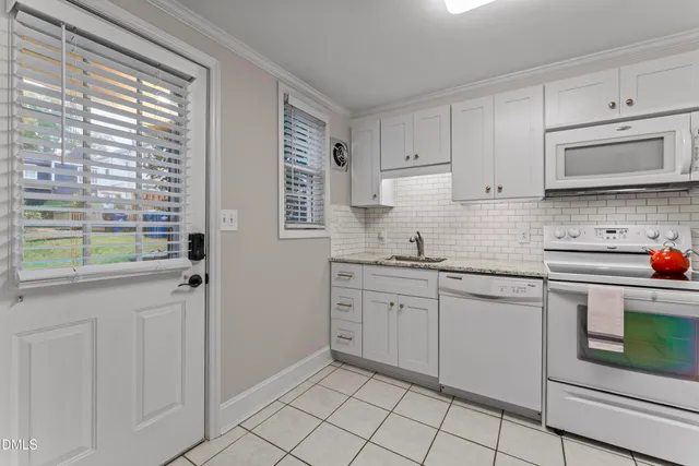 a kitchen with granite countertop white cabinets stainless steel appliances a sink and a window
