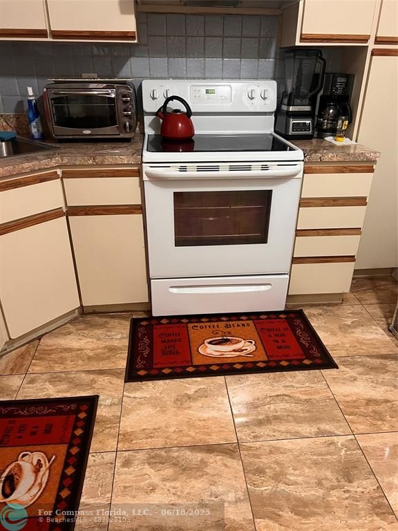3461 Cocoplum Circle, Unit 3431 Coconut Creek, FL 33063 - Photo 5 of 16 a kitchen with a stove and cabinets