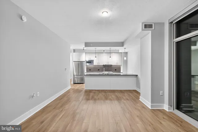 a view of a kitchen with kitchen island a sink wooden floor and stainless steel appliances